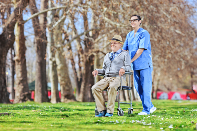 Male nurse pushing a senior in wheelchair in park