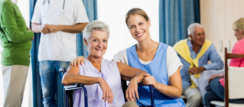 caregiver and senior woman in wheelchair smiling
